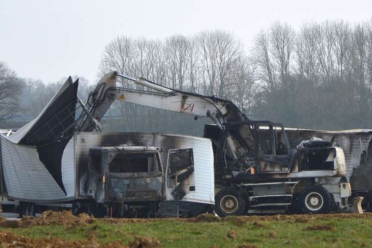 The vans sit near a highway exit after the hijackers abandoned and burned them about 30 miles from the site of the attack.