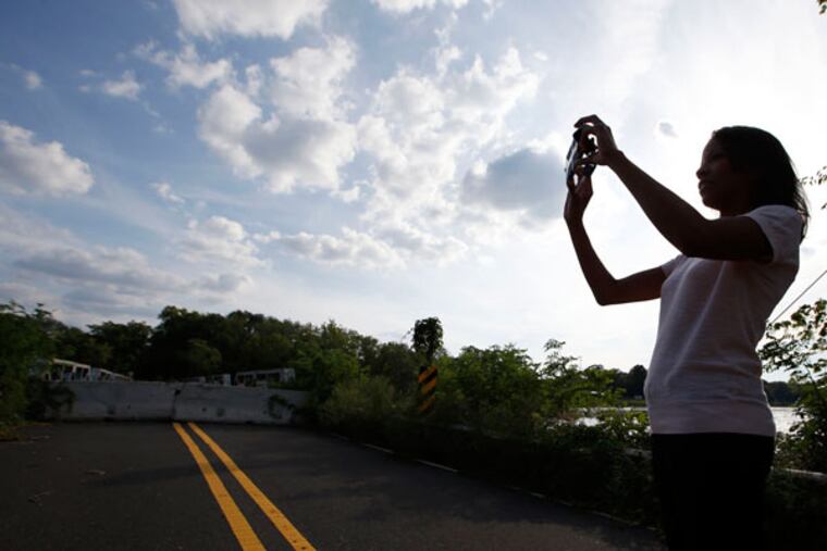 Lori Howard photographs the Centerton Bridge, which crosses the Rancocas Creek near I-295. Howard started a Facebook group for people who want the bridge to be repaired and reopened to traffic. (YONG KIM / Staff Photographer)