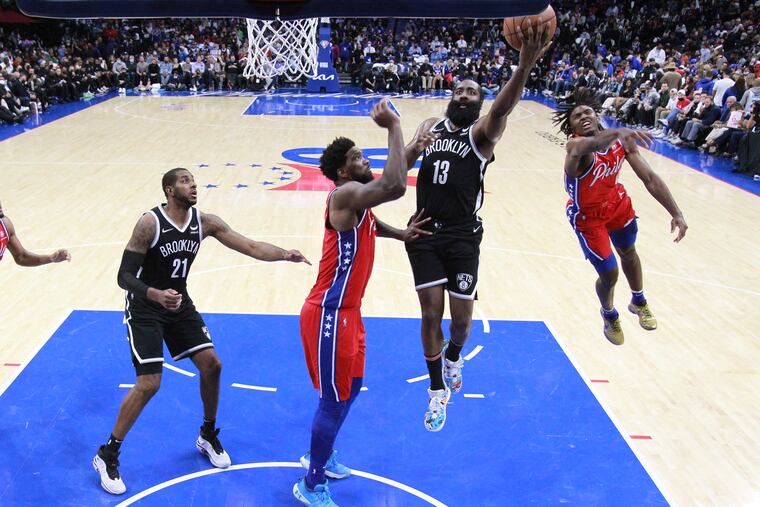 James Harden going up for a shot between Joel Embiid, center, and Tyrese Maxey during the Sixers' home opener at the Wells Fargo Center on Oct. 22, 2021.