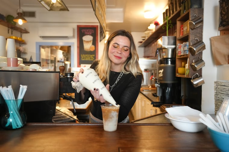 Zoe Tanner pipes marshmallow whip onto a speciality latte at Loretta's, a coffee shop in Society Hill.
