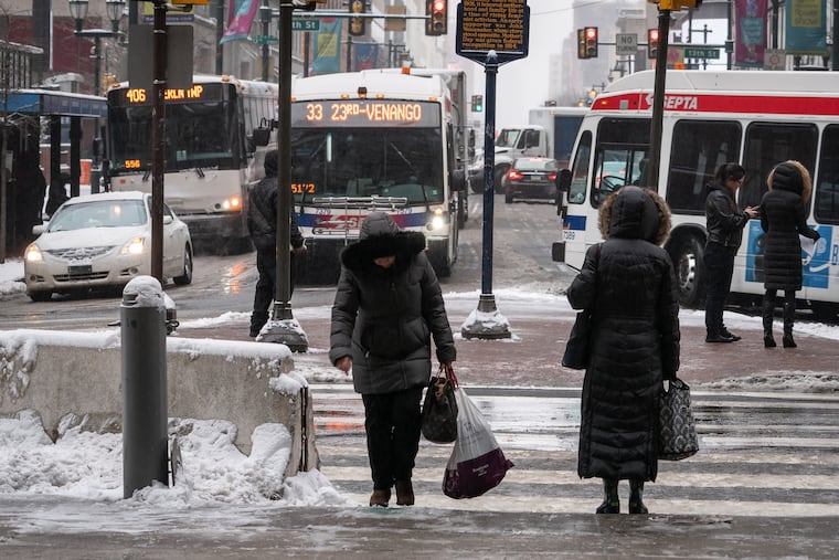 Pedestrians and drivers navigate slush and snow at the East side of City Hall last week.