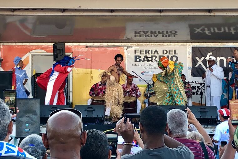 Music group Hermanos Ayala performs at the 35th Feria del Barrio, at Fifth Street and Lehigh Avenue, joined by two vejigantes on Sunday.