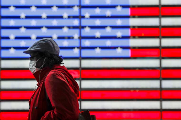 A pedestrian wearing a protective mask during the coronavirus pandemic walks along Seventh Avenue in Times Square, Saturday, May 23, 2020, in New York.