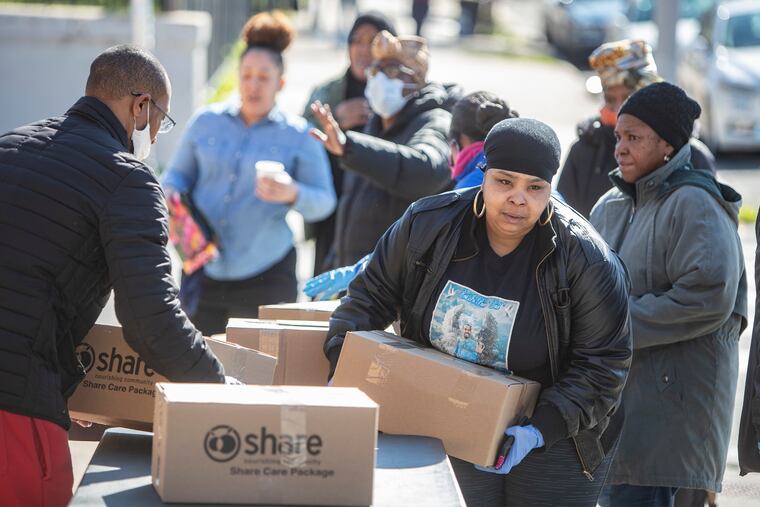 A woman picks up a box of canned goods from Share Food Program for her family at the Hank Gathers Memorial Recreation Center. Because of the spread of the coronavirus, 400 hundred cases of food were distributed to area residents at the center at 2501 Diamond Street last week. Food sites are supported by the city, Share, and Philabundance. The cases were gone in 30 minutes.