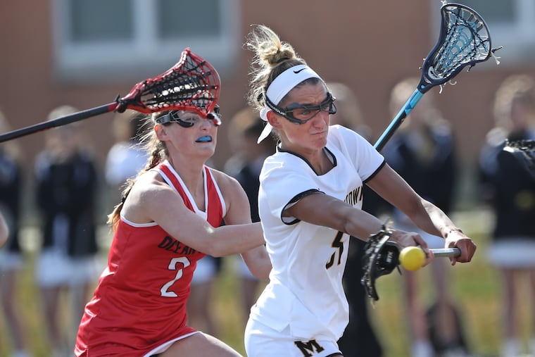 Moorestown's Kayla Frank (right) scores despite defense from Ocean City's Molly Reardon in Wednesday's season-opening girls' lacrosse game.