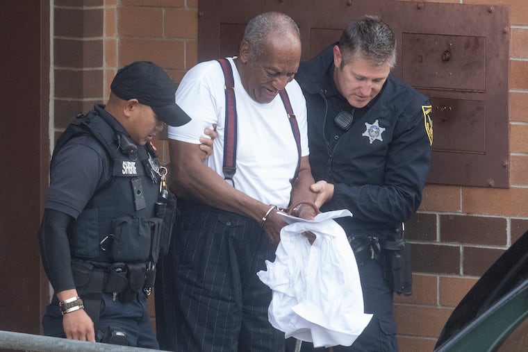 Bill Cosby is escorted by police in handcuffs as he exits the Montgomery County Correctional Facility in Norristown last September.