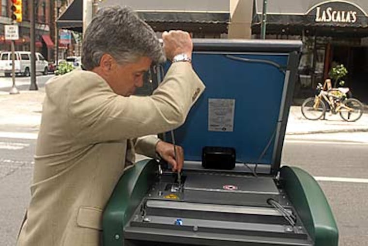 Rick Gaudette, VP of sales for the BigBelly trash compactor, lifts off its solar panel. The device is being tested at three sites in Center City. (RON TARVER / Inquirer)