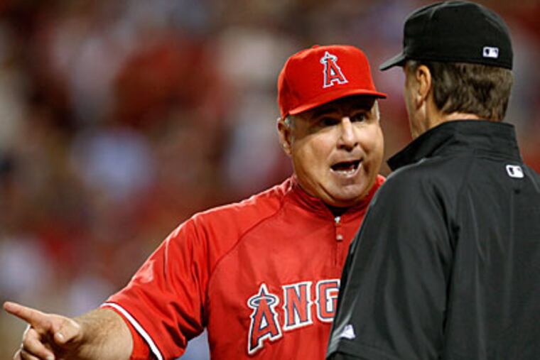 The Los Angeles Angels manager Mike Scioscia, left, talks with third base umpire Tim McClelland about a fifth inning double tag by Angels catcher Mike Napoli against New York Yankees Robinson Cano and Jorge Posada at Game 4 of the ALCS. Posada was called out and Cano remained on third as a fielder's choice. (AP Photo/Lenny Ignelzi)