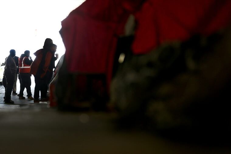 Outreach workers check on homeless people living under the Tulip Street bridge in Philadelphia. The city posted signs advising people they must leave the area under the bridge by May 30.