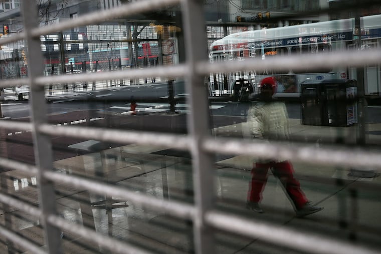 A pedestrian is reflected while walking past the shuttered Barnes and Noble on Temple University's campus in North Philadelphia on Tuesday. Bookstores and many other retail businesses were ordered on Thursday to remain closed indefinitely.