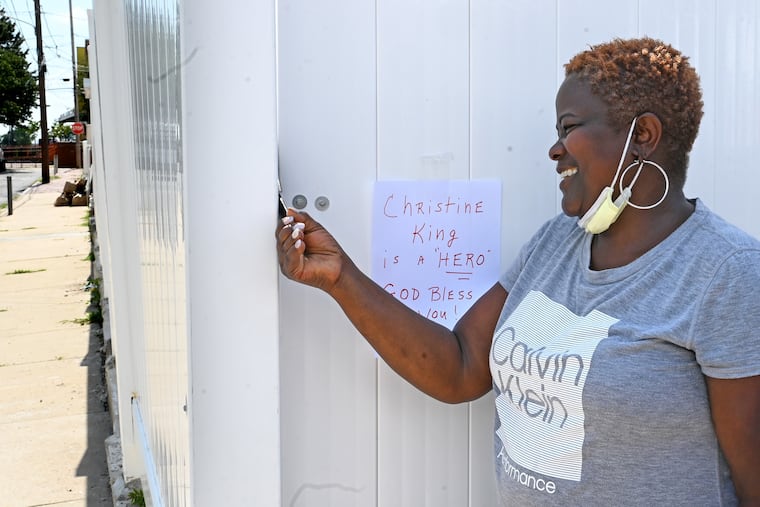 Christine King pauses outside the home where she works in Bridesburg on Aug. 2, 2022, where a neighbor taped a small handwritten sign: “Christine King is a HERO, God Bless you!” Last week she jumped out of her car on I-95 after she saw a man dangling a baby over an overpass.