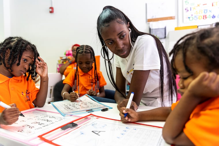Shahira Davis, owner of Little Scholars of the Future Learning Academy, helps Khabib Williams, 4, (right), practice writing the letter 'A.'