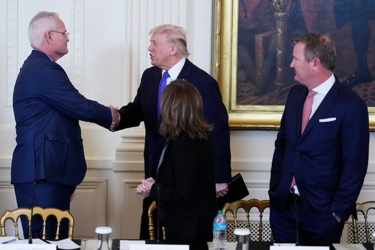 President Donald Trump greets Darren Woods, chief executive officer and chairman of ExxonMobil, while two other executives of oil companies look on during a meeting Friday in the East Room of the White House.