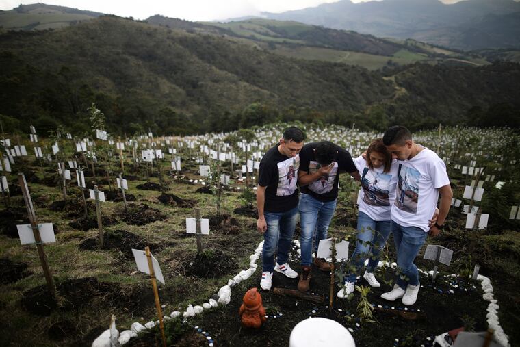 Relatives of Luis Enrique Rodriguez, who died of COVID-19, visit where he was buried on a hill at the El Pajonal de Cogua Natural Reserve, in Cogua, north of Bogota, Colombia.