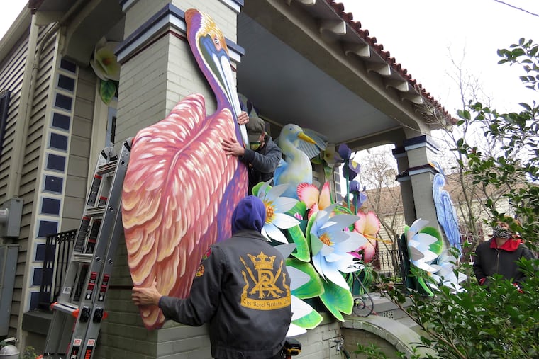 Parade float workers Travis Keene (left) and Joey Mercer position a pelican while fellow crew member Chelsea Kamm (right) looks on while decorating a house in New Orleans.