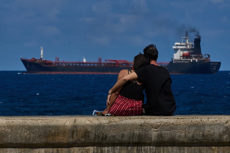 A couple sit on a seawall while watching a tanker ship exit the bay of Havana, Cuba, Saturday, Feb. 14, 2026.