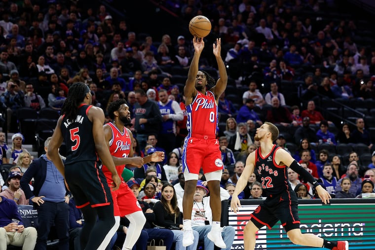 Sixers guard Tyrese Maxey shoots the basketball with teammate center Joel Embiid against Toronto Raptors guard Malachi Flynn (right) and forward Precious Achiuwa on Friday, December 22, 2023 in Philadelphia.