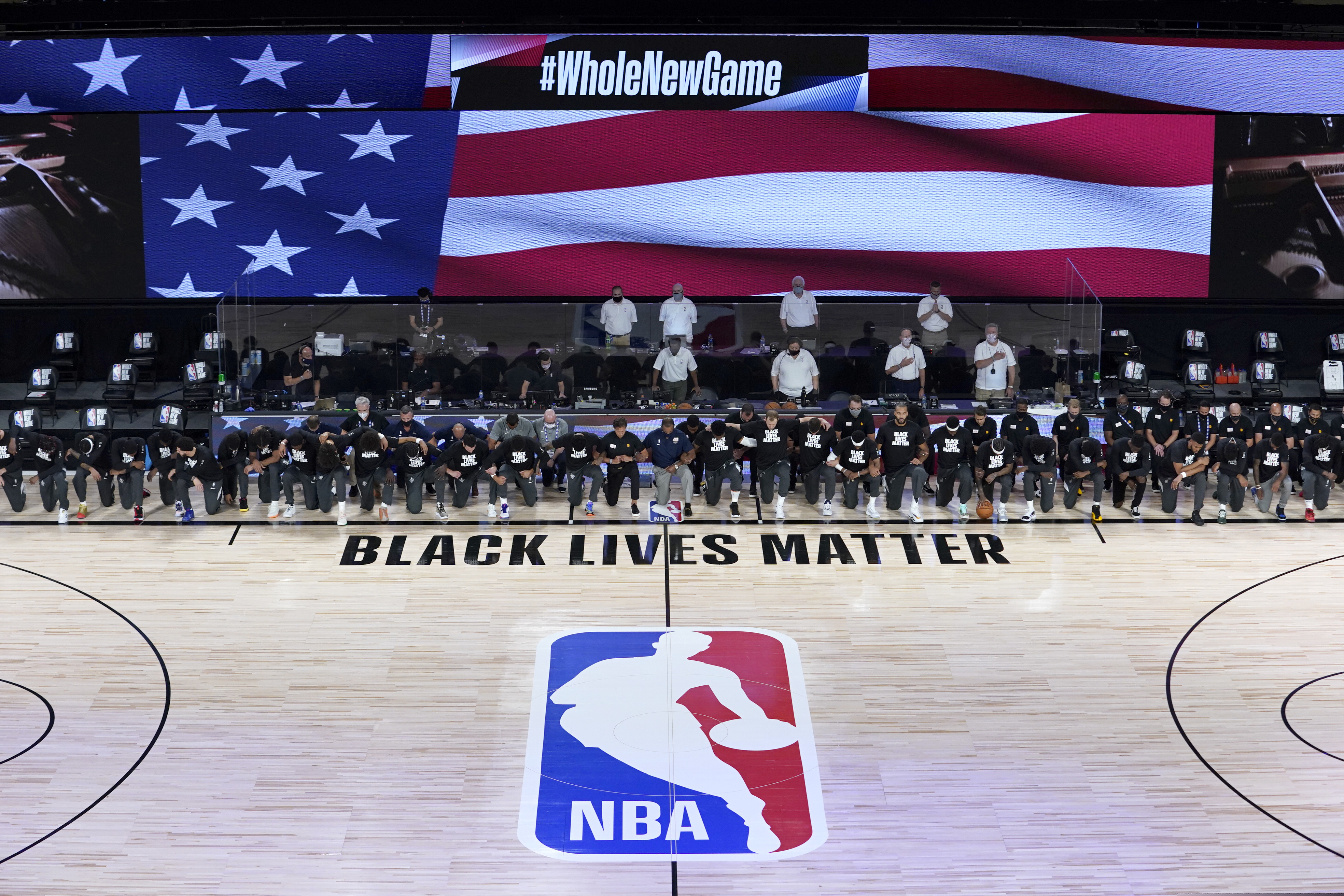 Members of the New Orleans Pelicans and Utah Jazz kneel together around the Black Lives Matter logo on the court during the national anthem before the start of an NBA basketball game Thursday.