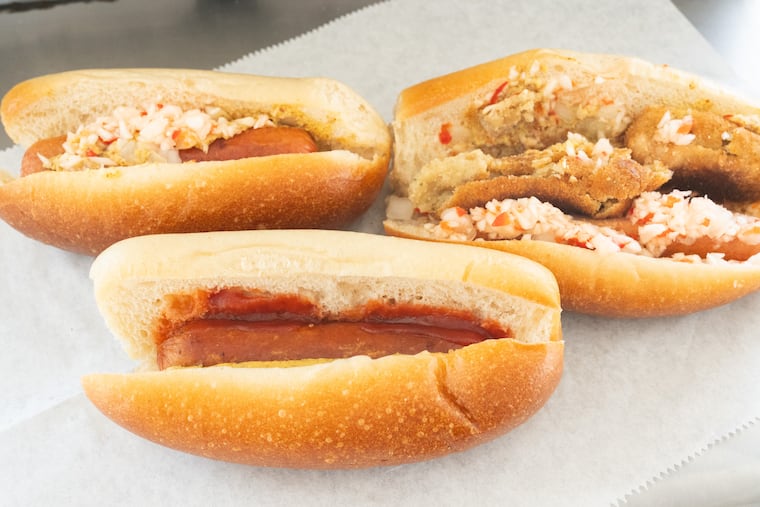 Standard Hot dog with ketchup and mustard front, hot dog with pepper hash back left, and hot dog with fish cake and pepper hash at Johnny's Hots, in Philadelphia, August 17, 2026.
