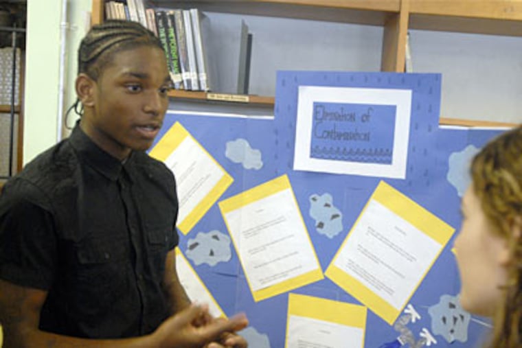 Justin White explains his team's project on how to make the school's drinking water safer to drink to biology teacher Stacy Driggin.