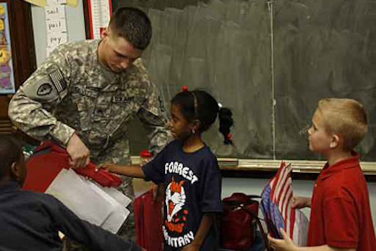 Sgt. Glenn Devitt Jr. receives class letters attached to paper flags from Maryam Hamdaza (center) and John Sullick (right) representing Mrs. Bloch's first grade class. (Michael S. Wirtz / Inquirer).