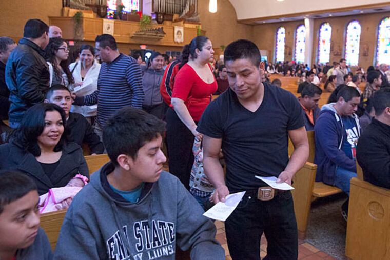A volunteer hands out brochures at Our Lady of Guadalupe encouraging cooperation with the police in solving crimes. Victims have been reluctant to come forward for fear of attention that could lead to deportation. ED HILLE / Staff Photographer
