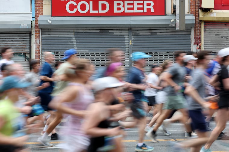 Runners pass a beer shop near Windrim Avenue during the 2025 Independence Blue Cross Broad Street Run. Spectators may opt more for hot coffee this year.