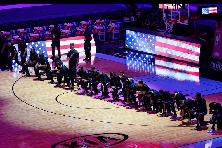 The Boston Celtics team kneels during the playing of the national anthem before their game against the Miami Heat.