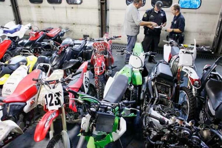 Philadelphia police from the Auto-squad Unit on Aug. 5 inspect ATVs and dirt bikes confiscated in the earlier raid in Kensington. (Joseph Kaczmarek / For the Daily News)