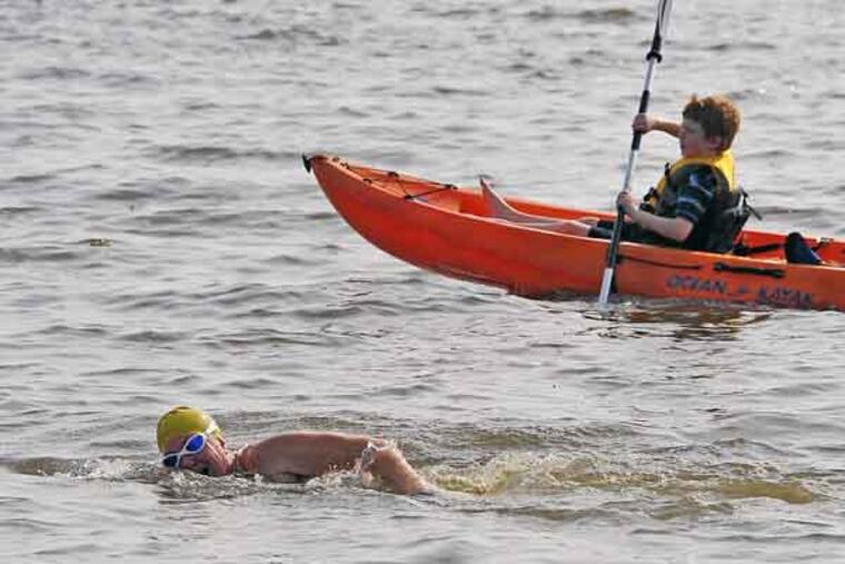 Meghan Wren swims in the Delaware Bay in Fortescue on July 12, 2013, as her son, Delbay Wren-Biggs, 8, paddles alongside her in a kayak. Wren says she's going to attempt to swim 13.1 miles across the Delaware Bay on Aug. 3. Wren plans to begin on the Delaware side of the bay and swim over to the New Jersey side. (AP Photo/The Daily Jurnal, Craig Matthews)