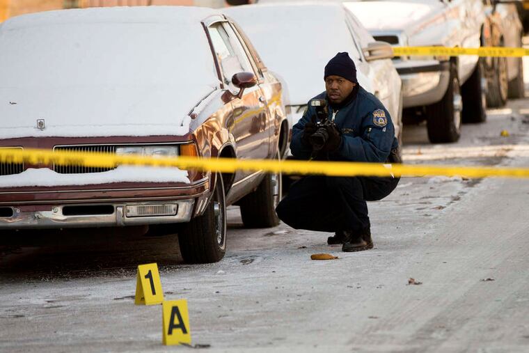 A member of the crime scene unit photographs evidence at the scene in Strawberry Mansion last January. After two years of historically low homicide numbers, Philadelphia saw its murder rate climb in 2015.