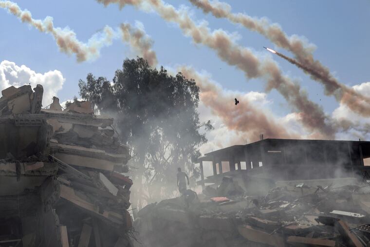 Rockets are fired from the Gaza Strip toward Israel over destroyed buildings following Israeli airstrikes on Gaza City, central Gaza Strip, on Thursday.
