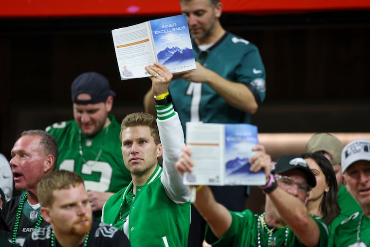 Eagles fans hold up the "Inner Excellence" book during Super Bowl LIX on Feb. 9. Author Jim Murphy landed a book deal with Grand Central Publishing Group.