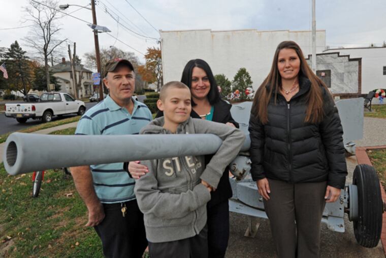 In Maple Shade, NJ the Spencer family and Tina Mikes, a veterans case manager, who helps them, on Nov. 15, 2013. Here, from left to right: Thomas Spencer, son Tommy Spencer, Jr., 14; wife Gwenann Spencer; and Mikes at a veterans memorial in Maple Shade. (APRIL SAUL/Staff)