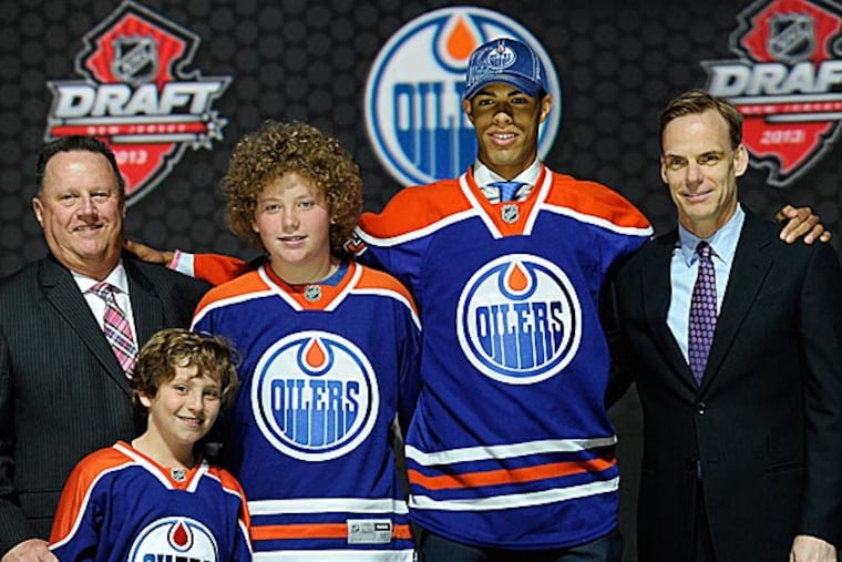 Darnell Nurse stands with officials from the Edmonton Oilers sweater after being chosen seventh overall in the first round. (Bill Kostroun/AP)