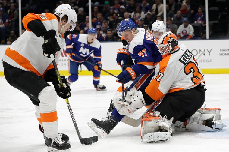 Travis Sanheim (left) steals the puck from in front of the Islanders' Leo Komarov as goalie Brian Elliott tries to defend in the second period.