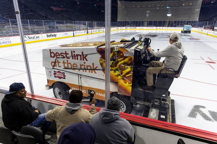(From left to right) Roy Carter, 55, of Olney, and Kirk Starchier, of South Philadelphia, 55, both equipment operators with Philadelphia's Department of Parks and Recreation, and Shawn Drumwright, 56, of Northeast Philadelphia, a heavy equipment operator with Parks and Recreation, watch and learn how the Zambonis work on the ice at the Wells Fargo Center in Philadelphia, on Friday.