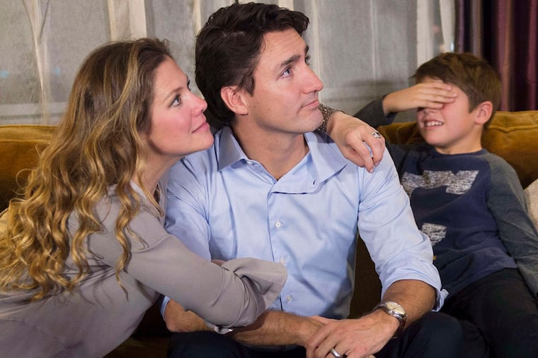 Xavier Trudeau, right, covers his eyes as Liberal leader Justin Trudeau watches the election results with his wife Sophie Gregoire at a hotel in downtown Montreal on Monday, Oct. 19, 2015.
