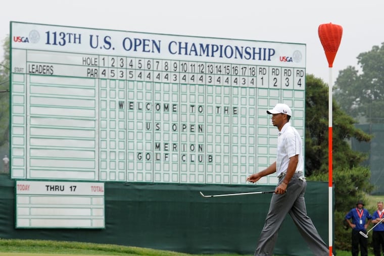 In this 2013 file photo, Tiger Woods walks past the leader board located at the 18th green at the Merion Golf Club in Ardmore during a practice round for the U.S. Open golf championship. On Tuesday, federal prosecutors in Philadelphia charged a U.S. Golf Association employee with stealing and reselling tickets to this and other Men's Open events.