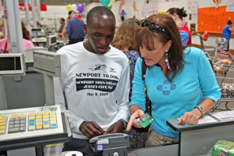 Lisa Buster, a sports agent, helps Silas Sang, one of several Kenyan runners she manages, with a debit-card purchase. (Michael Bryant / Staff Photographer)