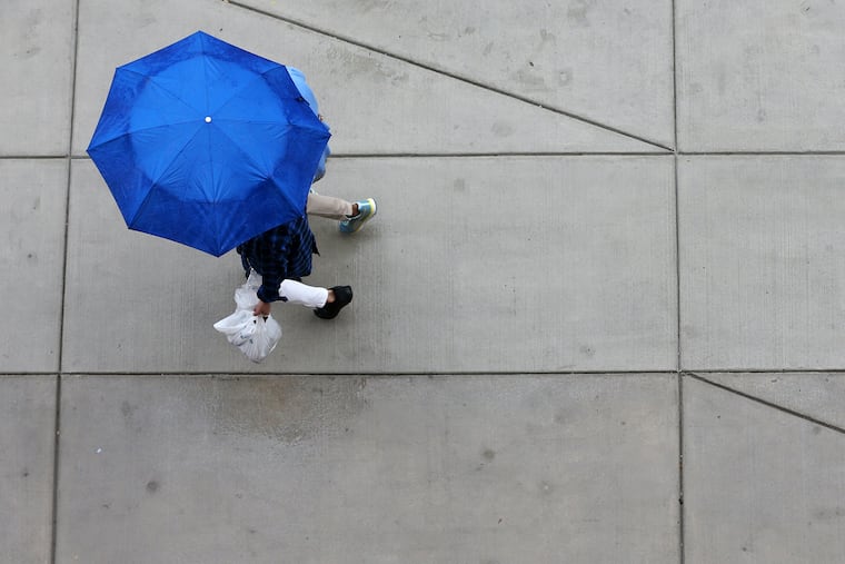 Pedestrians shield themselves from the rain on Market Street in Center City on Saturday, July 21, 2018.