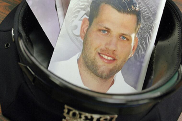 Officer Tim Taylor, of the 35th District, carries pamphlets from fallen officers’ funerals in his police hat. (James Heaney / Staff Photographer)