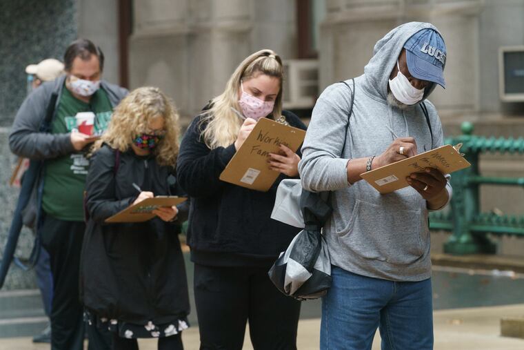 Voters fill out forms while waiting in line to apply for and submit mail ballots at City Hall in Philadelphia on Monday.