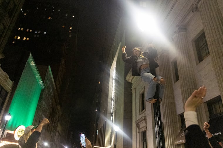 A person climbs on a light pole to celebrate the Eagles winning along with many other fans who attempt to climb the light poles in Philadelphia on Jan. 29.