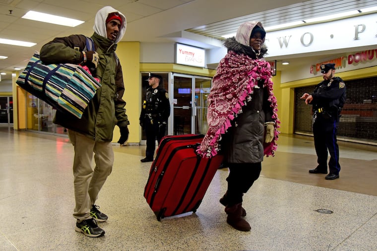 Jamal Phelps (left) and Charlene Bennett, both in their 40s, move toward the exits as SEPTA Transit Police arrive after midnight to clear homeless people out of Suburban Station before locking the doors for the night.