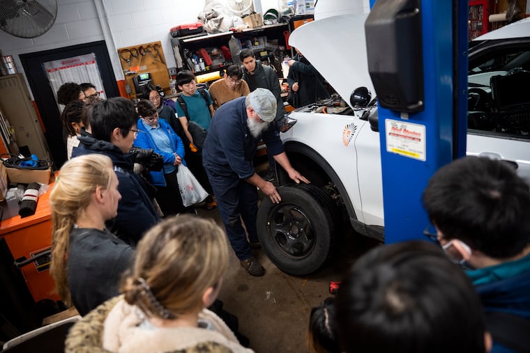 Students watch as mechanic Steve Lucash changes a tire during a Wintersession course at Princeton University.