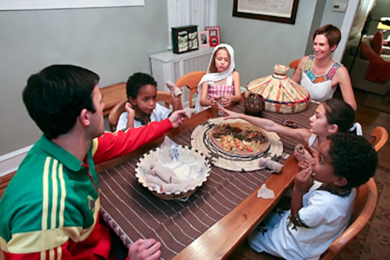 The Rupertus family in Mount Airy — (from left) dad Chris, Mihretu, Lucy, mom Kate, Annie, and Abel — share an Ethiopian meal to honor the adopted boys’ culture. (Steven M. Falk / Staff Photographer)