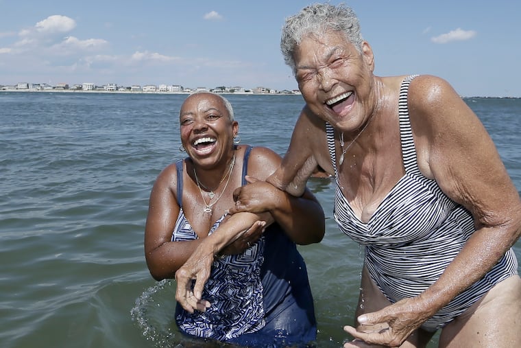 Traci Scott (left) and Delores Mitchell hold on to each other and laugh after they both dove under the water at the Caspian Ave. beach in Atlantic City.