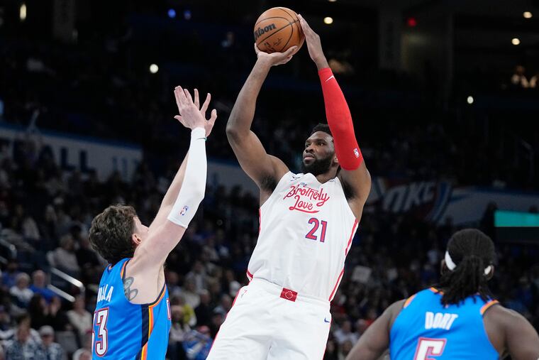 Philadelphia 76ers center Joel Embiid (21) shoots between Thunder center Mike Muscala, left, and guard Luguentz Dort during Saturday's game in Oklahoma City. Sixers won the game, 115-96.
