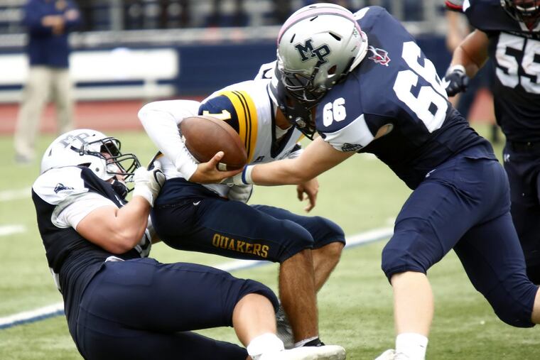 Malvern Prep defensive players Ryan Betz (left) and Jack Walker (right) combine to sack Penn Charter’s Will Samuel in the fourth quarter.